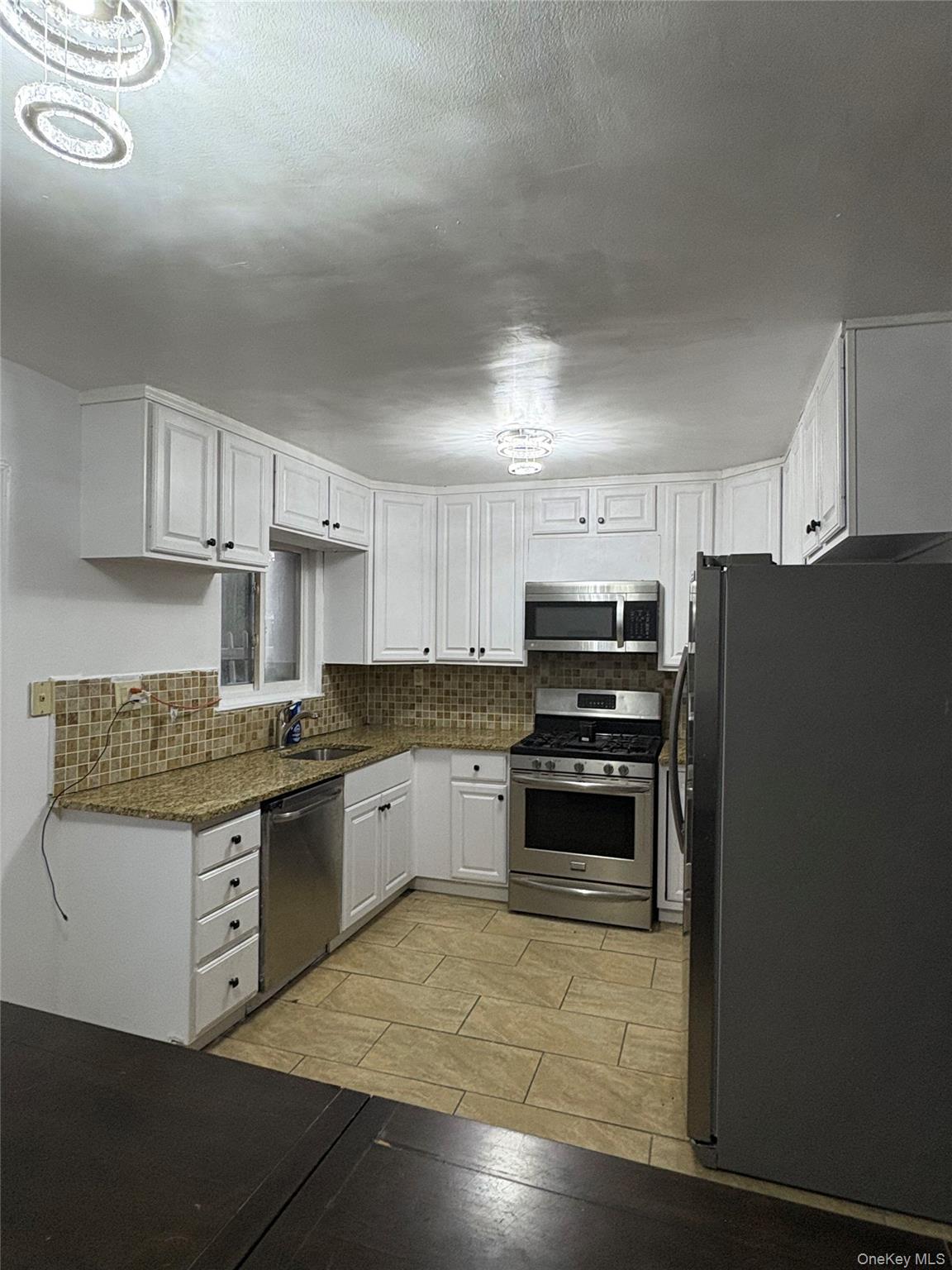 269 Balcom Avenue Bronx, NY 10465 - Photo 4 of 20 Kitchen with appliances with stainless steel finishes, tasteful backsplash, white cabinetry, wood tiled floors, and dark stone counters
