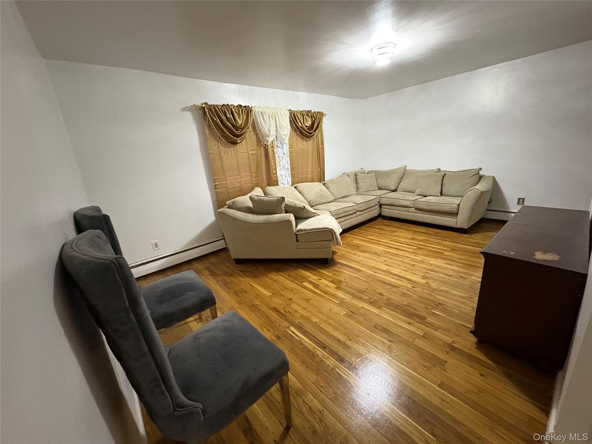 269 Balcom Avenue Bronx, NY 10465 - Photo 10 of 20 Living room featuring wood finished floors and a baseboard heating unit