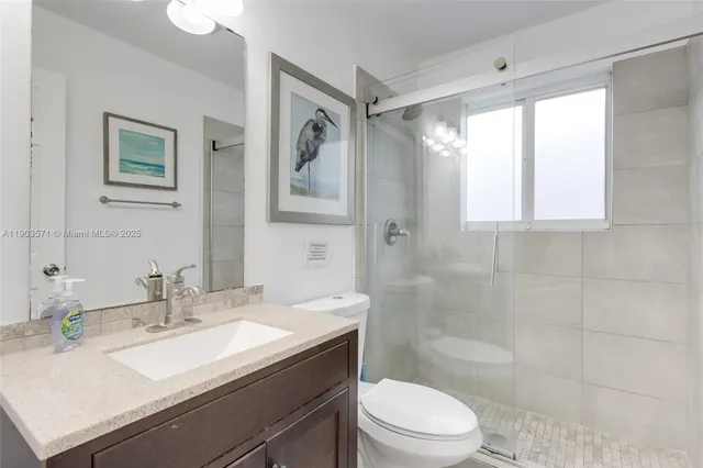 a bathroom with a granite countertop sink a toilet and shower
