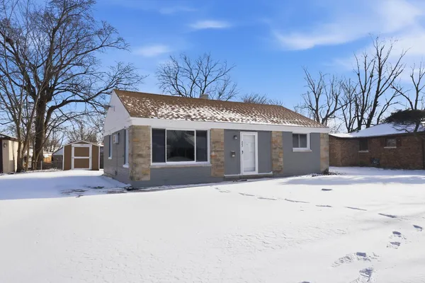a front view of a house with a yard covered in snow