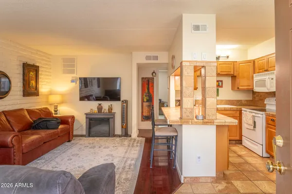 a living room with furniture a flat screen tv and a refrigerator