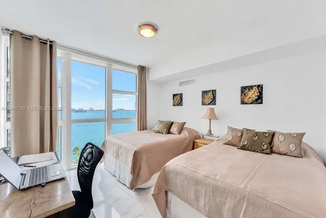 a bedroom with two beds and large window