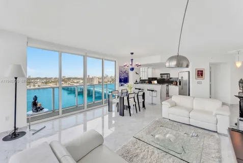 a living room with furniture a kitchen view and a large window