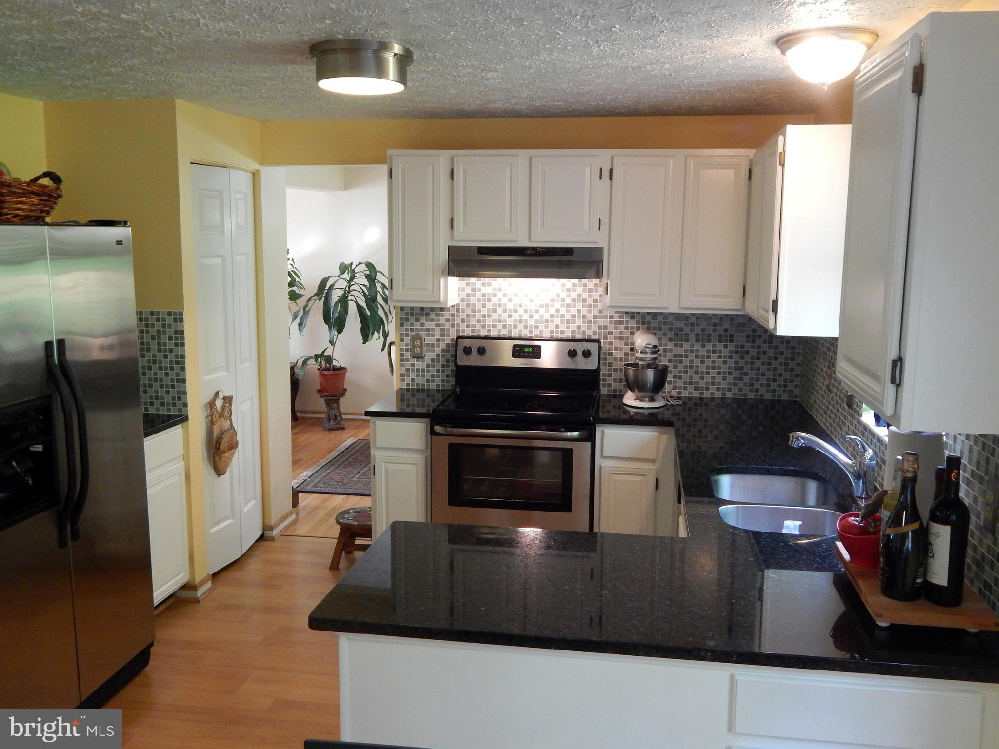 5776 Heming Avenue Springfield, VA 22151 - Photo 8 of 25 a kitchen with stainless steel appliances a stove a refrigerator a sink a counter space and cabinets