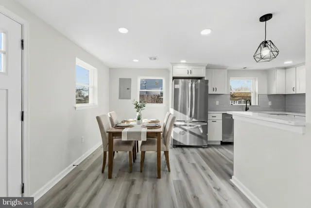 a kitchen with stainless steel appliances a dining table chairs stove refrigerator and cabinets