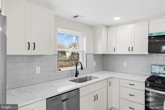 a kitchen with white cabinets a sink and dishwasher