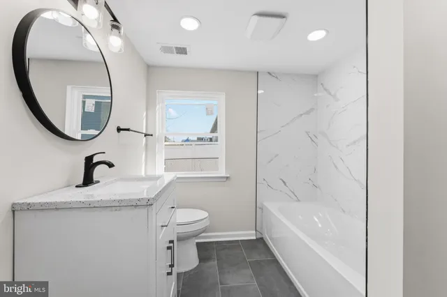 a bathroom with a granite countertop sink a toilet and a mirror