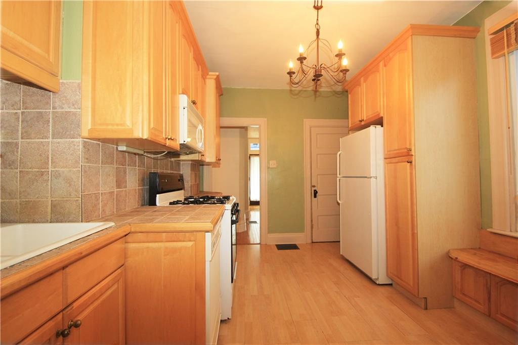 915 Malvern Road Pittsburgh, PA 15202 - Photo 9 of 23 This alternate view of the kitchen shows the entry hall in the background and the door to the basement to the right. The custom bench seat under the window to the right adding character to the room.