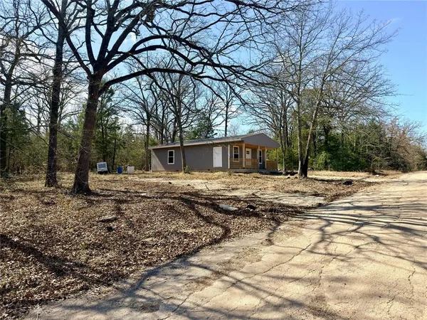a backyard of a house with large trees and outdoor seating