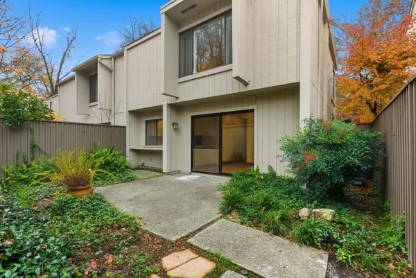 a view of a house with a small yard plants and large tree