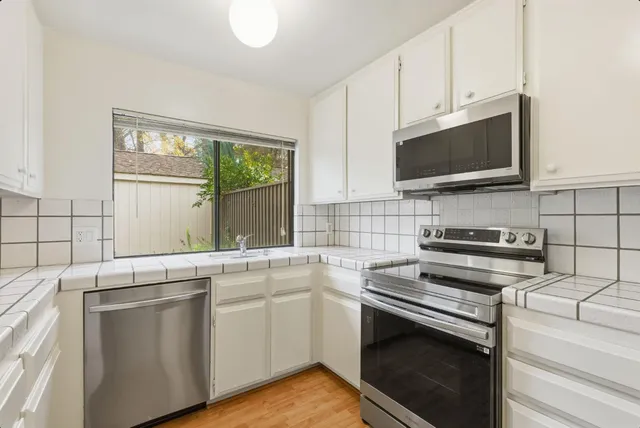 a kitchen with stainless steel appliances a stove microwave and sink