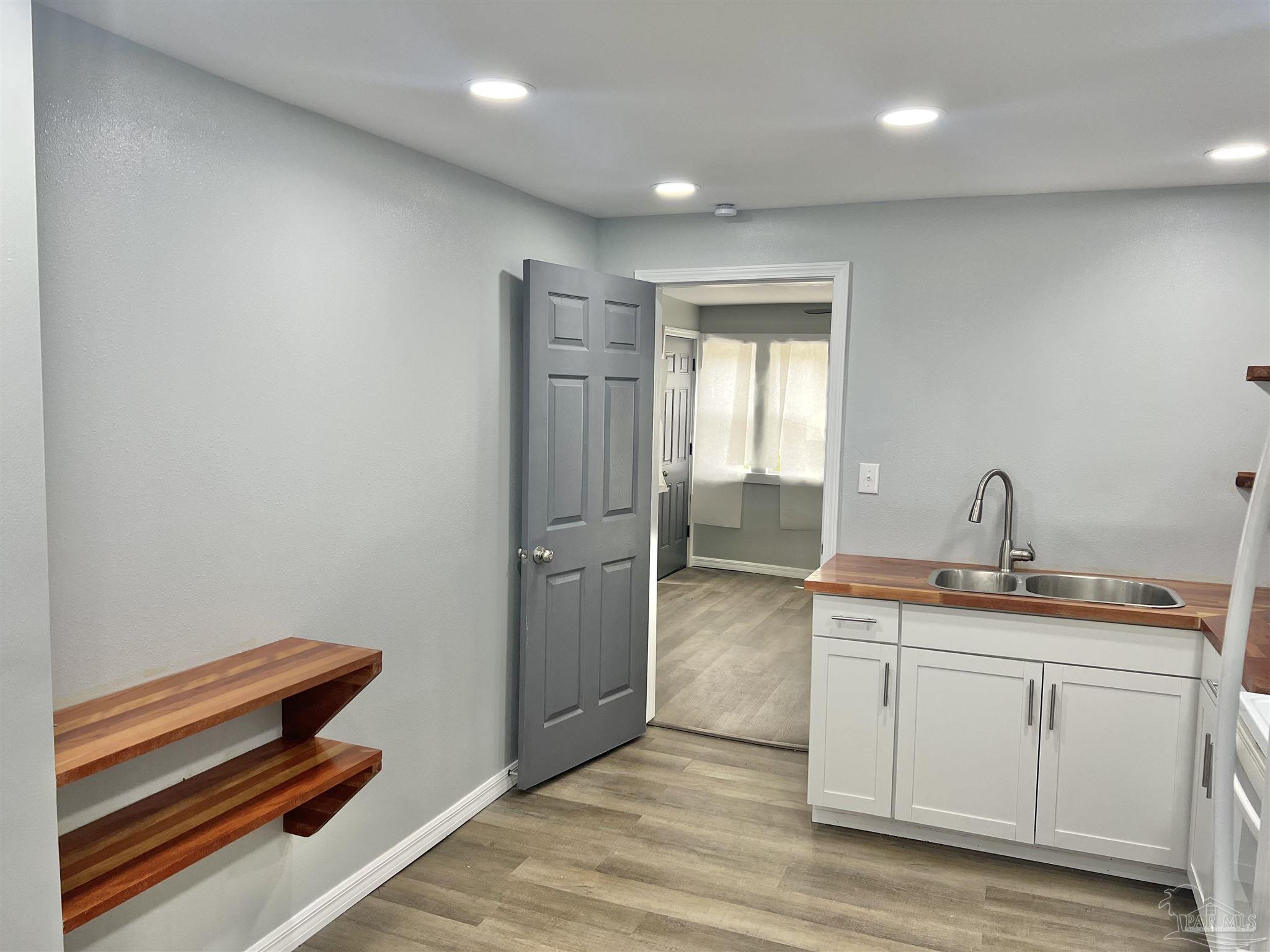 102 W Avenue Atmore, AL 36502 - Photo 9 of 25 a hallway with a chair and wooden floor