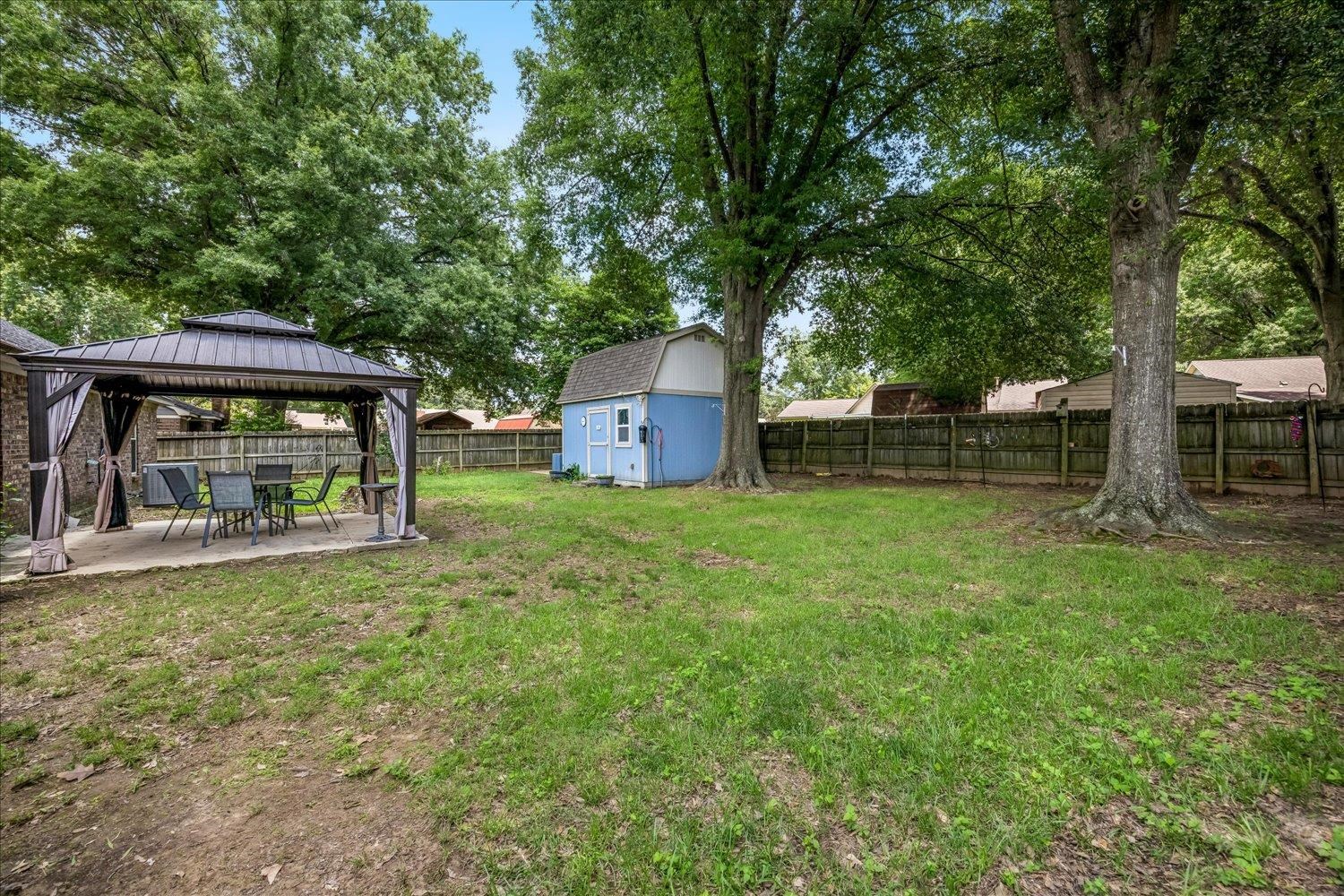 3284 Altruria Road Bartlett, TN 38134 - Photo 25 of 28 Expansive backyard featuring a covered patio with a metal gazebo, a detached storage shed, a wood privacy fence, and mature trees
