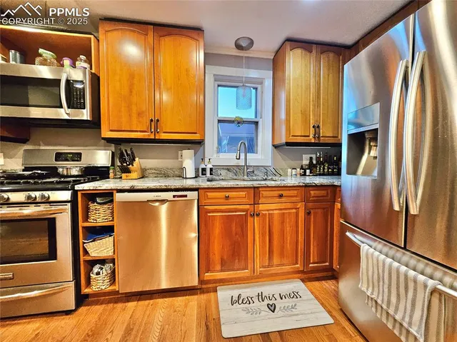 a kitchen with stainless steel appliances granite countertop a refrigerator a stove and a sink