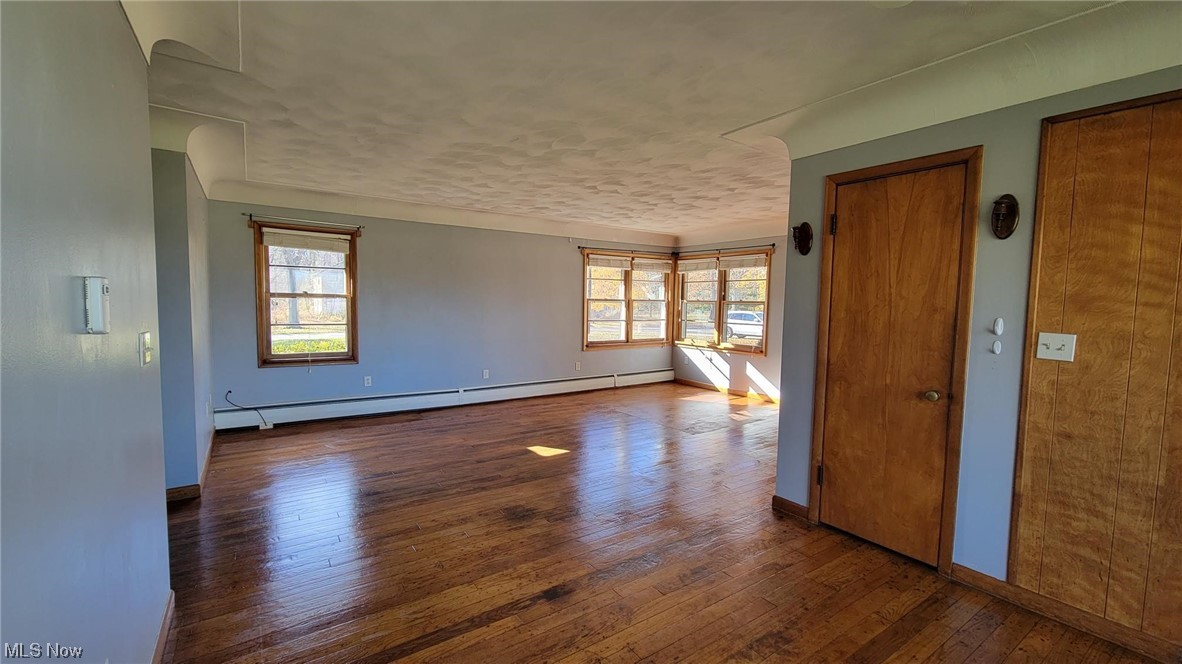 405 Bryan Road Milan, OH 44846 - Photo 5 of 35 Family room featuring plenty of natural light, dark hardwood flooring, and a baseboard heating unit