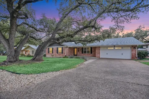 a front view of a house with a garden and trees