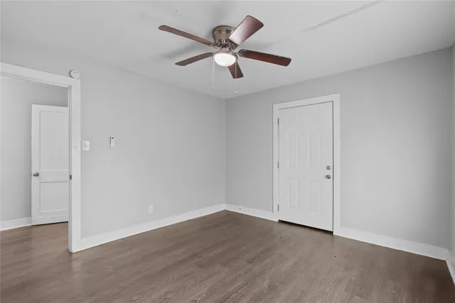 an empty room with wooden floor and ceiling fan