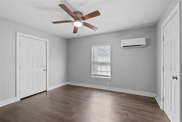 an empty room with wooden floor chandelier fan and windows