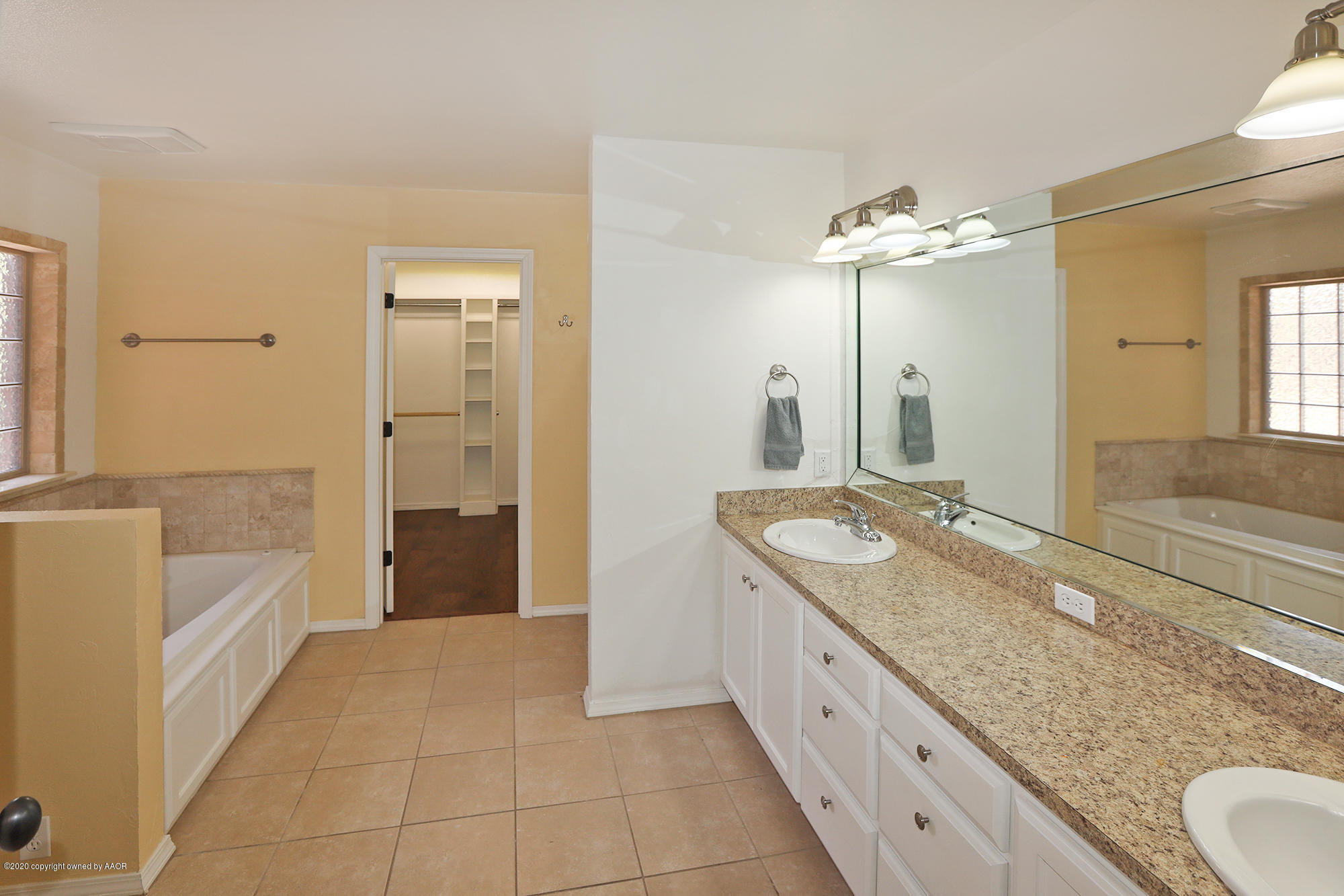 7003 Nick Street Amarillo, TX 79119 - Photo 12 of 34 a spacious bathroom with a granite countertop sink a mirror a bathtub and shower