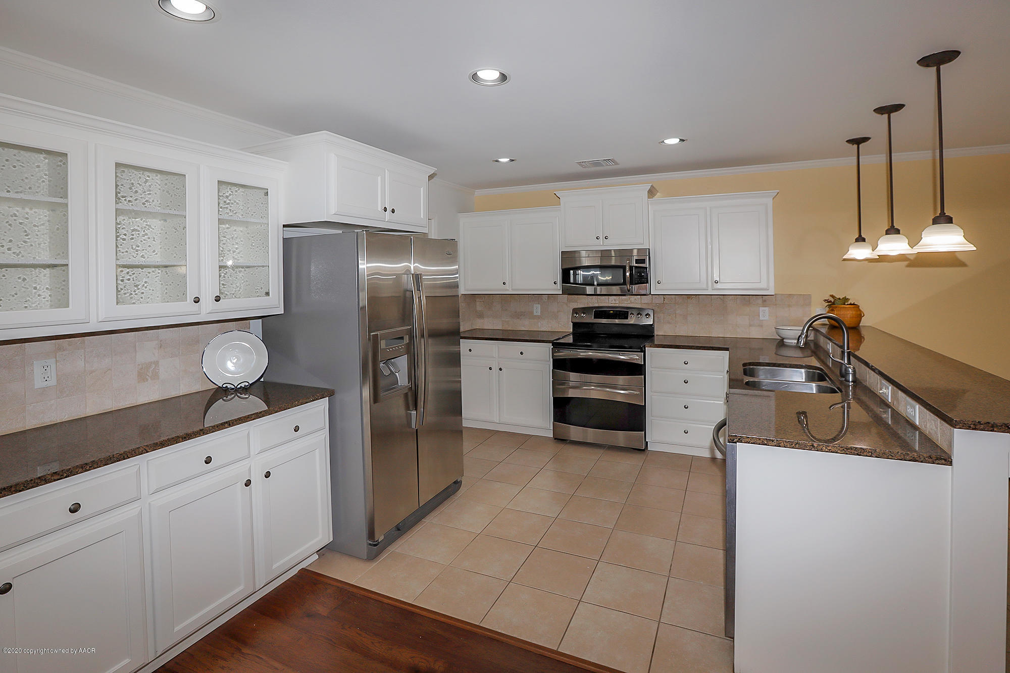 7003 Nick Street Amarillo, TX 79119 - Photo 8 of 34 a kitchen with granite countertop a refrigerator oven a sink dishwasher and white cabinets next to a window
