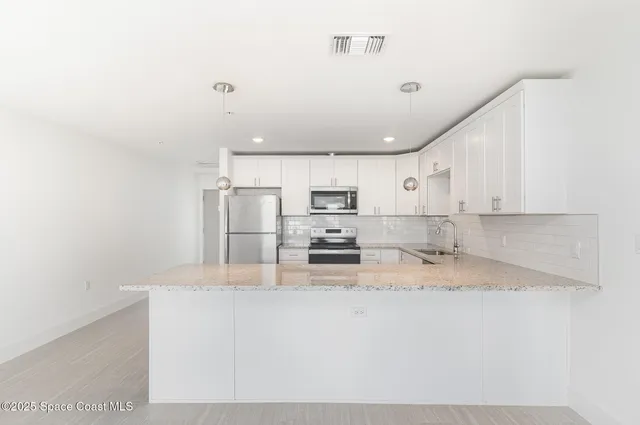 a kitchen with stainless steel appliances granite countertop a sink refrigerator and cabinets