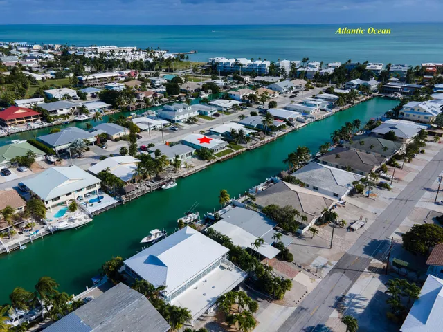 an aerial view of a city with lots of residential buildings and ocean view in back