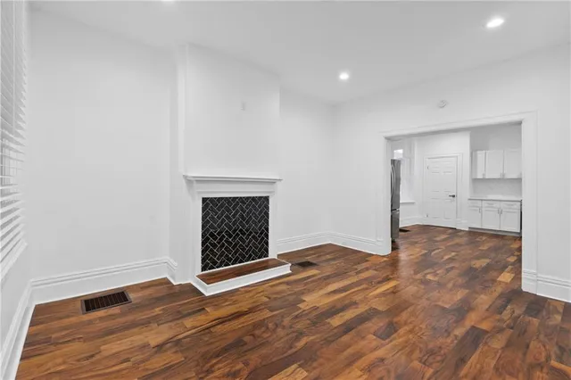 a view of empty room with wooden floor and fireplace