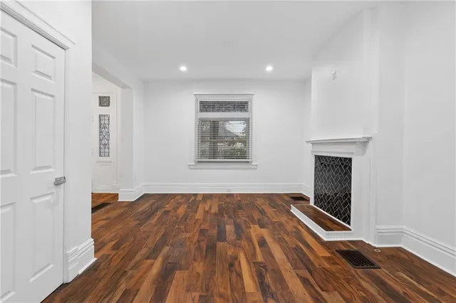 a view of an empty room with wooden floor fireplace and a window