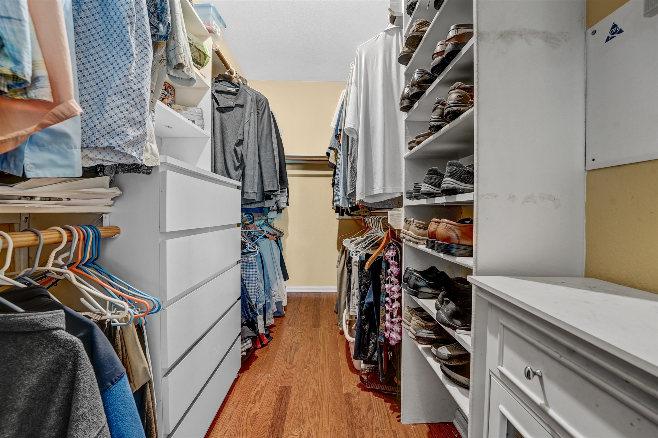 2521 Amen Corner Road Pflugerville, TX 78660 - Photo 20 of 40 Custom closet system featuring wood-finish flooring, multiple hanging rods, built-in shelving, integrated drawers, and a dedicated shoe rack