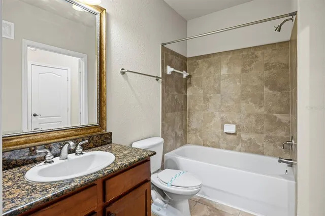 a bathroom with a granite countertop sink a mirror a bathtub and shower