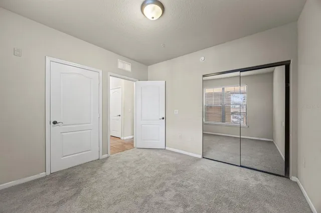 a view of an empty room with closet and a window