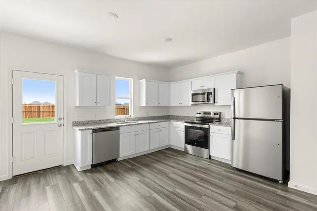 a kitchen with granite countertop appliances a sink and a refrigerator