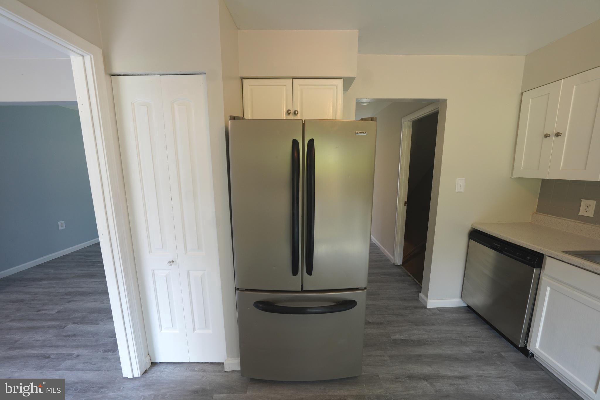 8997 Centerway Road Gaithersburg, MD 20879 - Photo 20 of 71 a view of a refrigerator in kitchen and an empty room in wooden floor