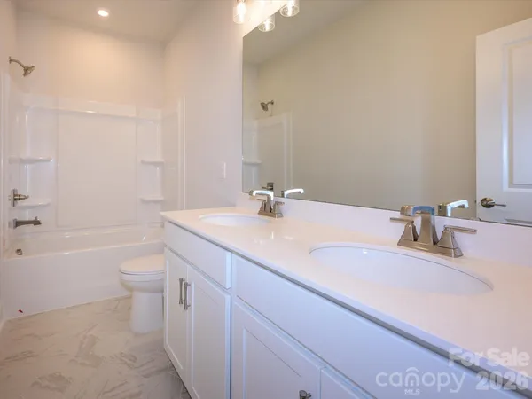a bathroom with a granite countertop sink a toilet and a large mirror