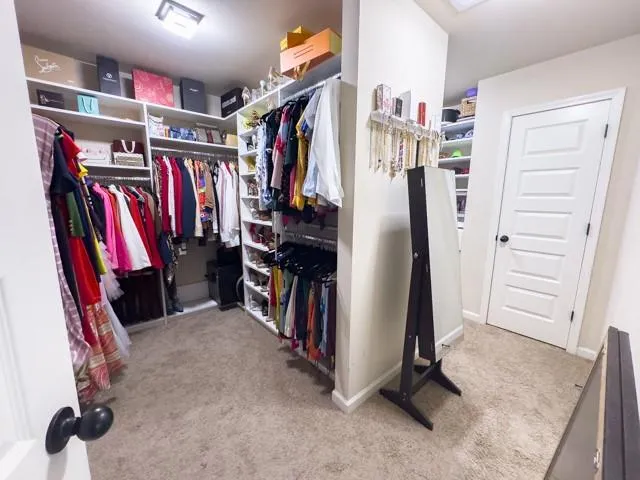 a view of walk in closet with clothes and shoes