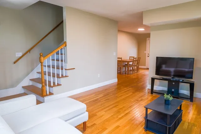 a living room with couches and a dining table with wooden floor