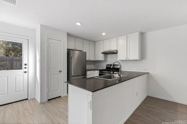 a kitchen with stainless steel appliances granite countertop a sink a refrigerator a microwave and cabinets