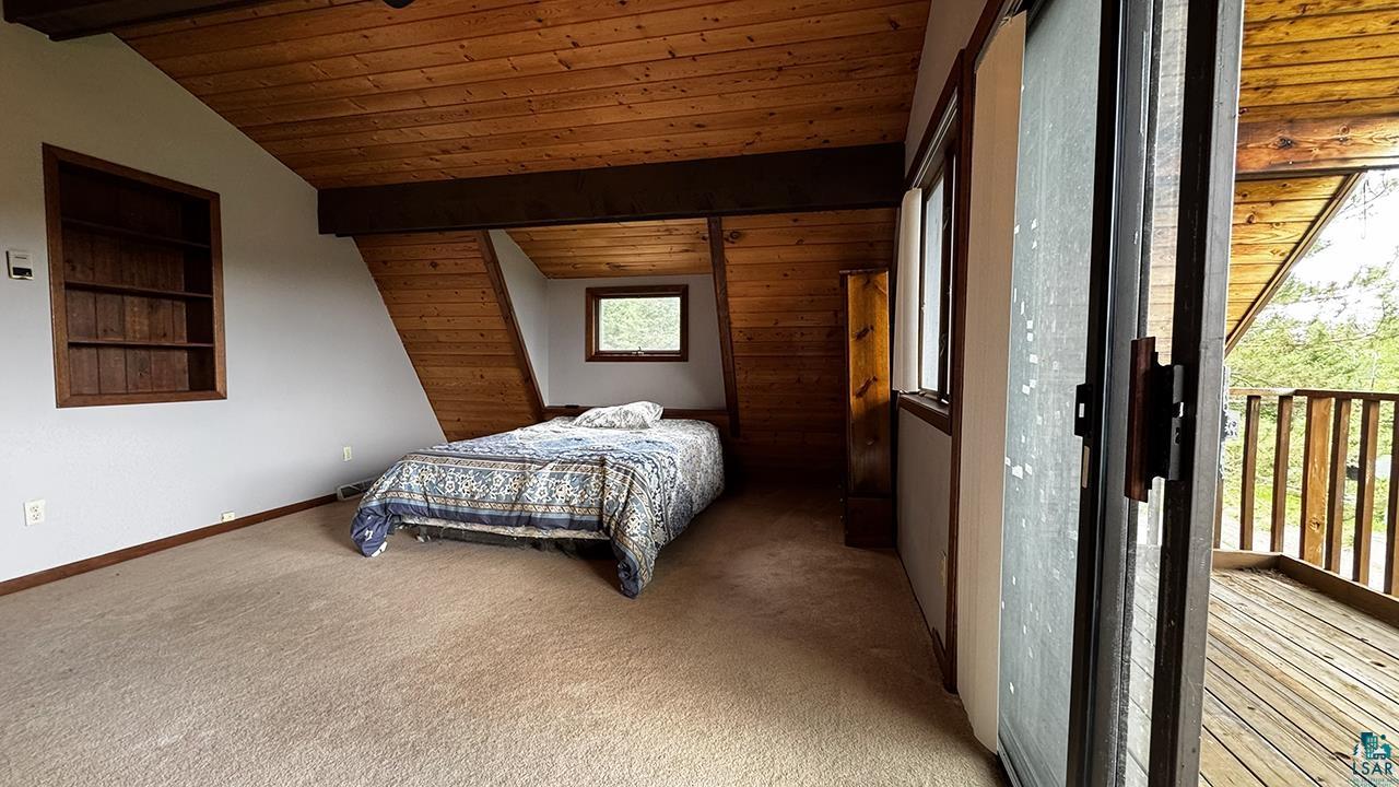 9289 Heino Road Angora, MN 55703 - Photo 16 of 37 Carpeted room featuring a wood-planked ceiling, exposed wood beams, and a built-in wall niche with shelving