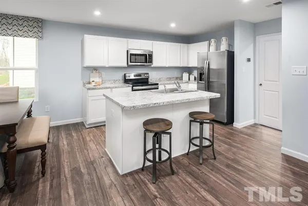 a kitchen with kitchen island wooden floors white appliances and cabinets