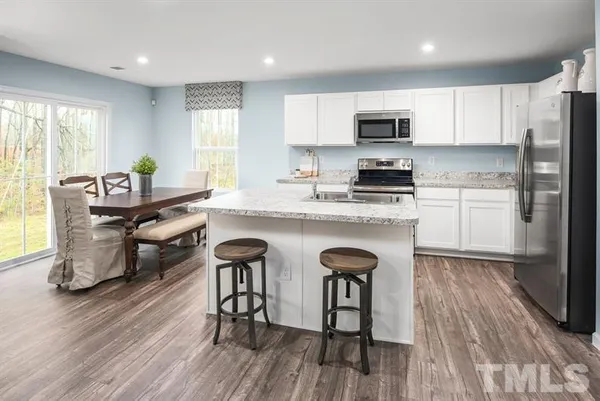 a kitchen with stainless steel appliances granite countertop wooden floors a stove a microwave a center island and a window