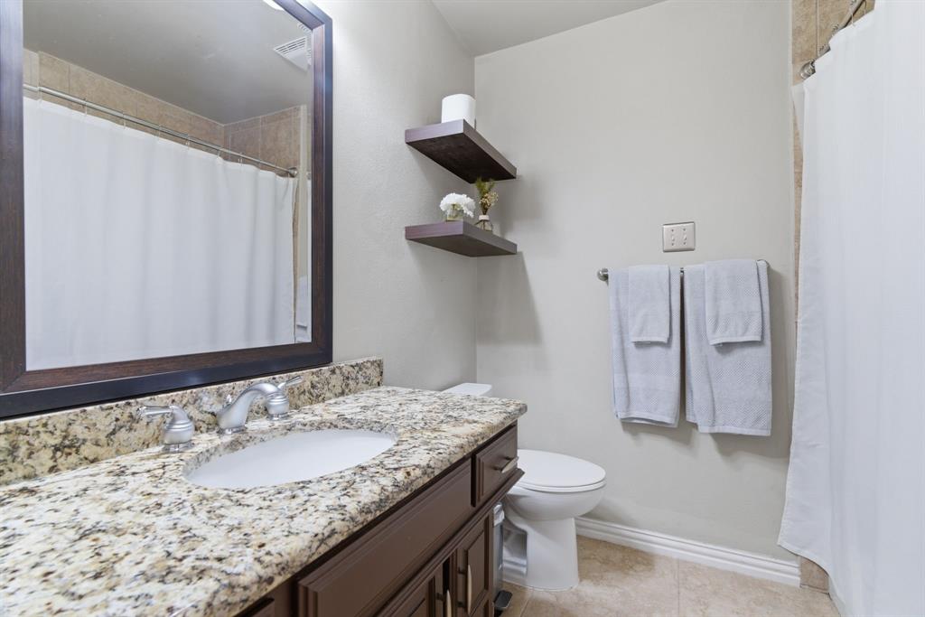 2307 Castle Rock Road Carrollton, TX 75007 - Photo 26 of 34 Bathroom featuring a vanity with a granite countertop and an undermount sink, a framed mirror, and two floating shelves
