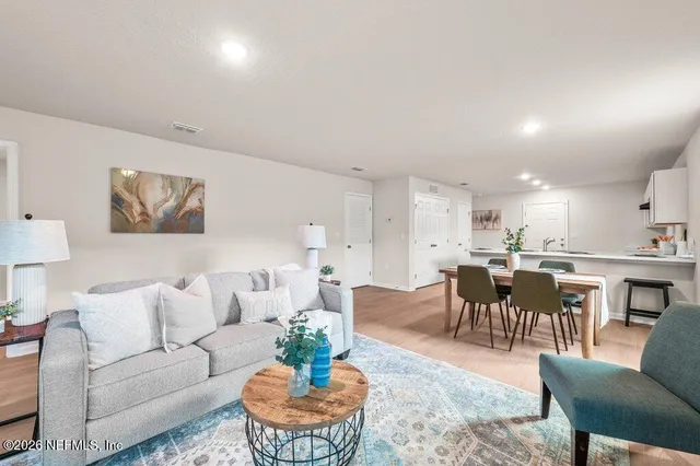 a living room with furniture potted plant and kitchen view