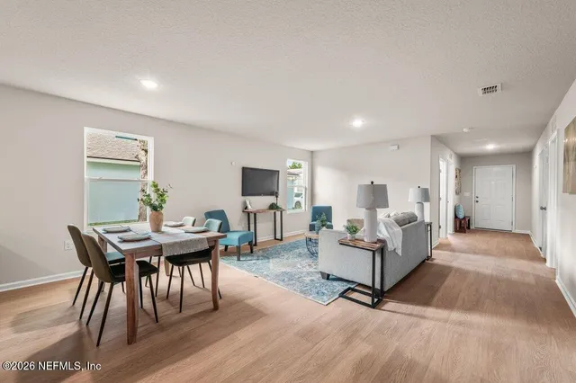 a living room with furniture a wooden floor and a kitchen view