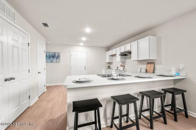 a kitchen with a dining table chairs and white cabinets