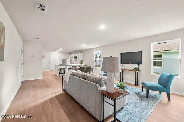 a living room with furniture a flat screen tv and a window