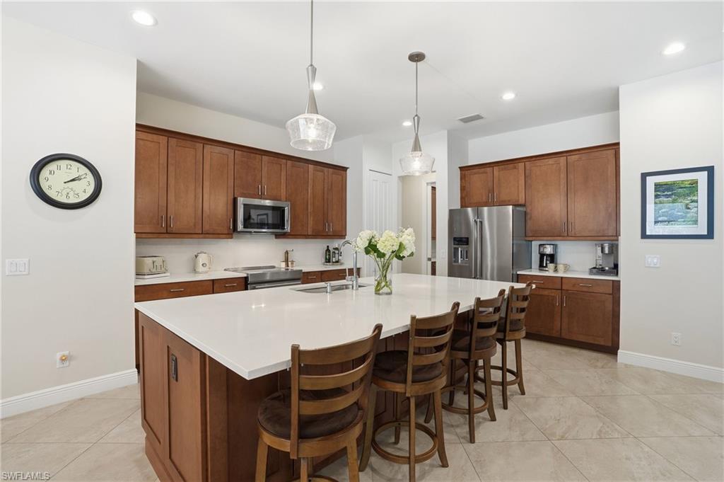 3707 5th Avenue Southwest Naples, FL 34117 - Photo 5 of 45 Kitchen with a breakfast bar, pendant lighting, brown cabinetry, and recessed lighting