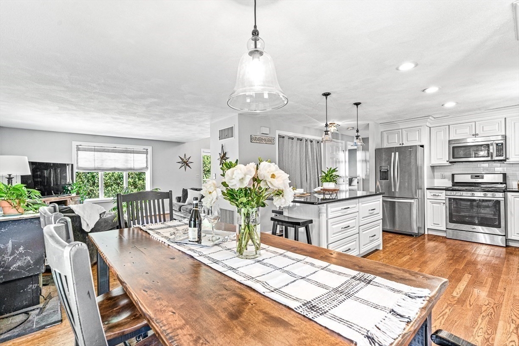 27 A Andrews Farm Road Boxford, MA 01921 - Photo 13 of 37 a kitchen with stainless steel appliances kitchen island granite countertop a stove a refrigerator a kitchen island a dining table and chairs with the wooden floor
