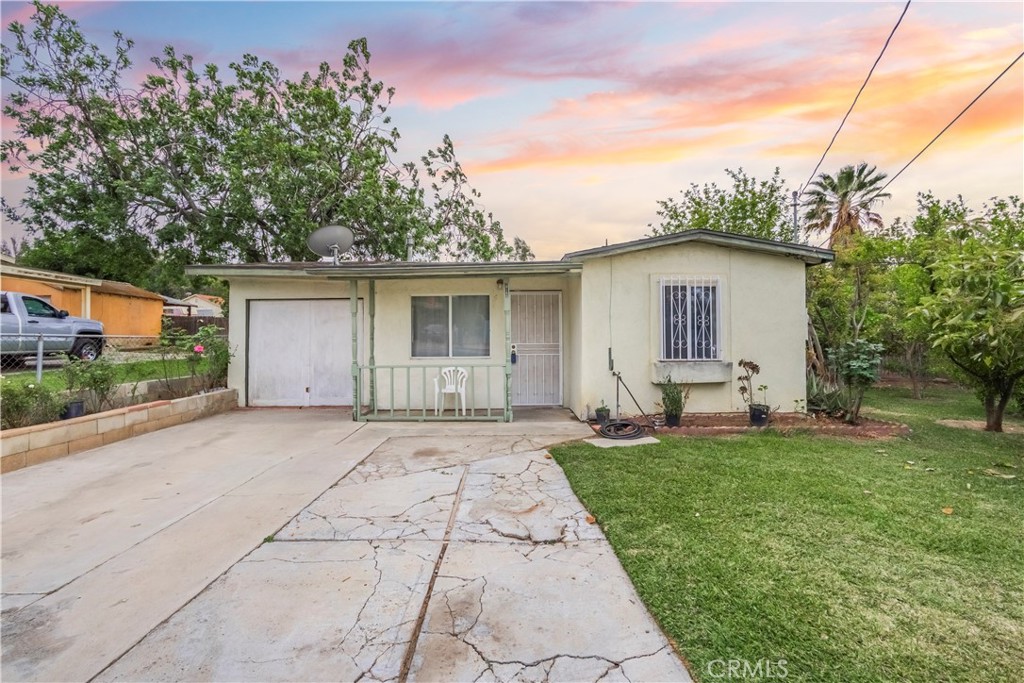 a white house that has a small yard and large trees
