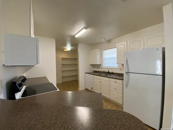 a kitchen with a refrigerator a stove a sink and white cabinets