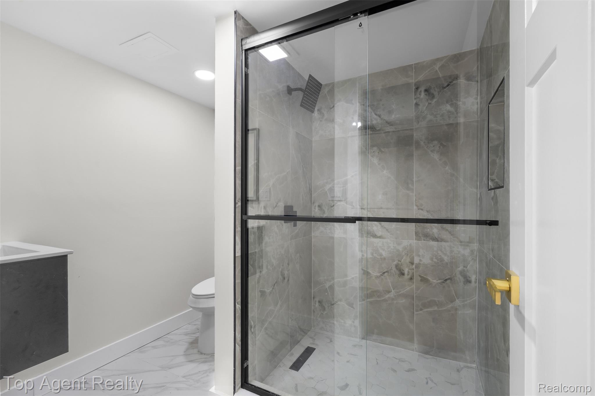 29863 Fall River Road Southfield, MI 48076 - Photo 30 of 50 Walk-in shower featuring a frameless glass enclosure with black hardware, marble-look tiled walls, a built-in shower niche, and a contrasting dark shower drain